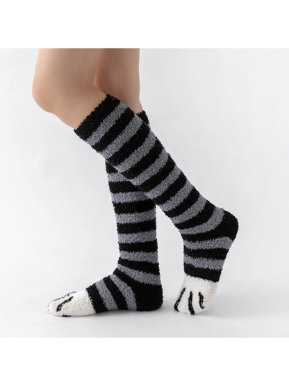 Black and gray striped fuzzy knee-high socks with white cat-paw toes, side view