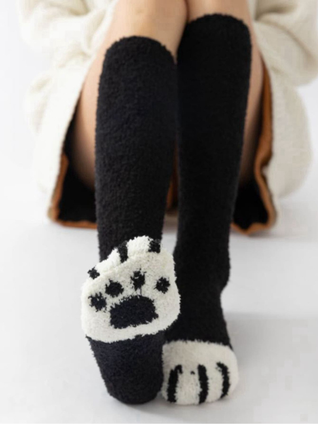 Black fuzzy knee-high socks showing a white cat-paw sole and striped toe