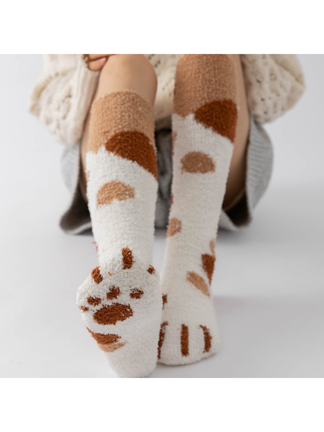 Cream fuzzy knee-high socks showing the tan and brown cat-paw sole design