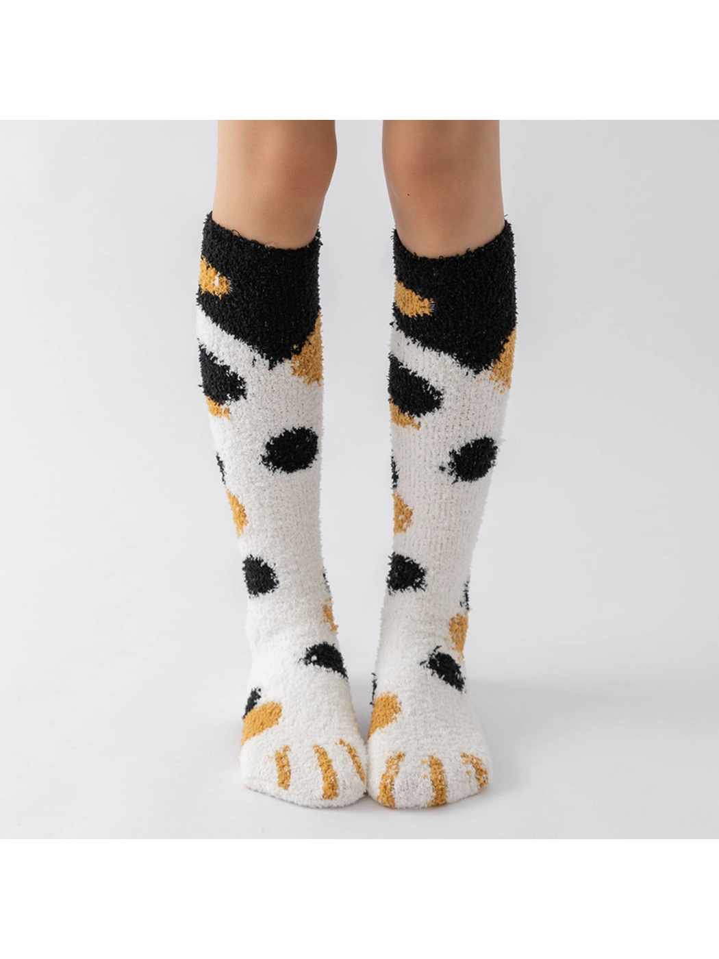 Cream fuzzy knee-high socks with black and mustard spots and cat-paw toes, front view