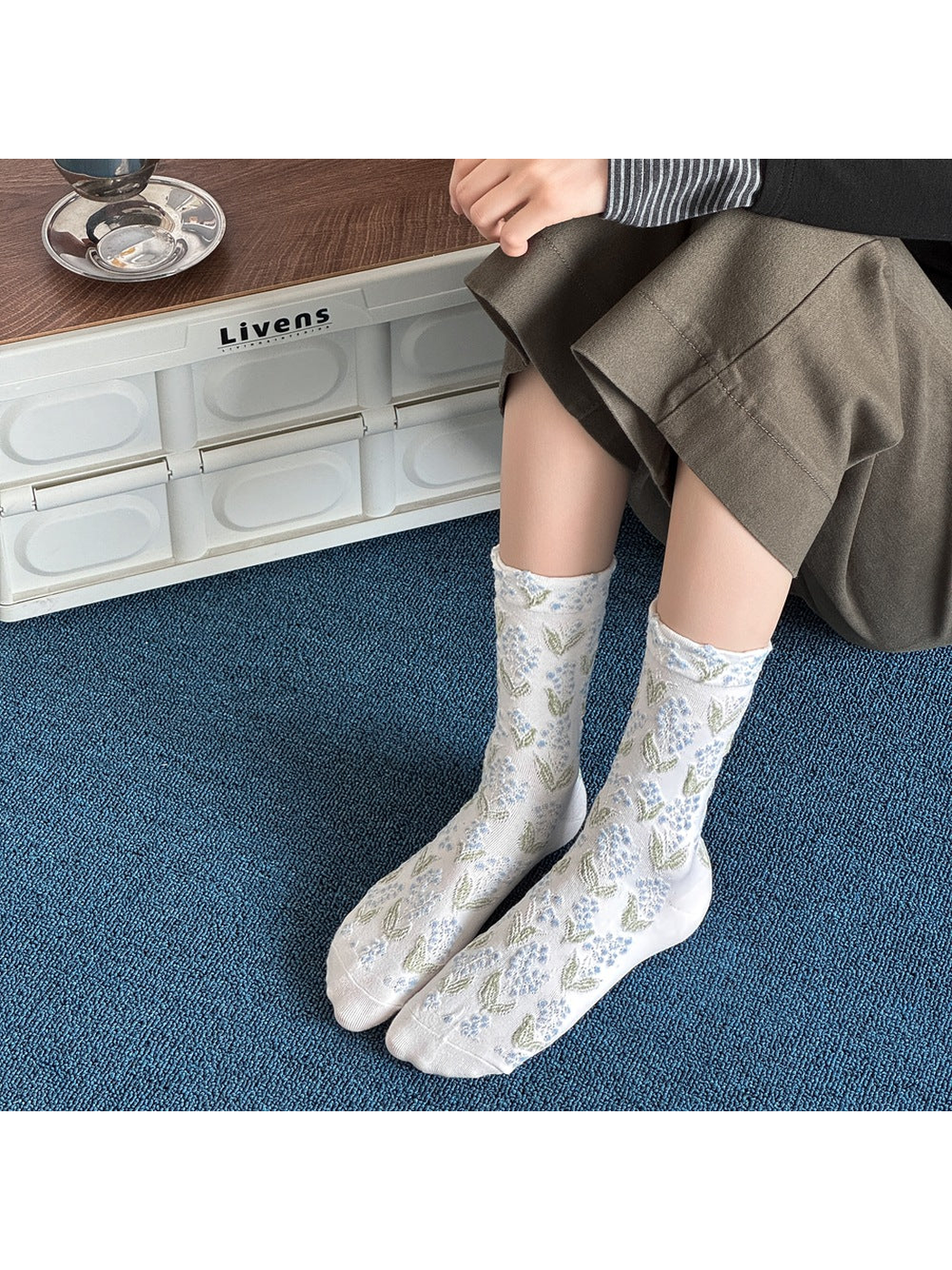 White crew socks with blue floral motifs worn against a blue carpet