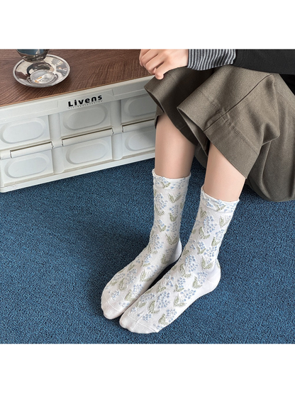 White crew socks with blue floral motifs worn against a blue carpet