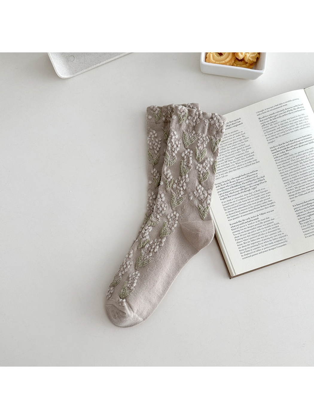 Greige crew sock with raised floral motifs and a ruffled cuff
