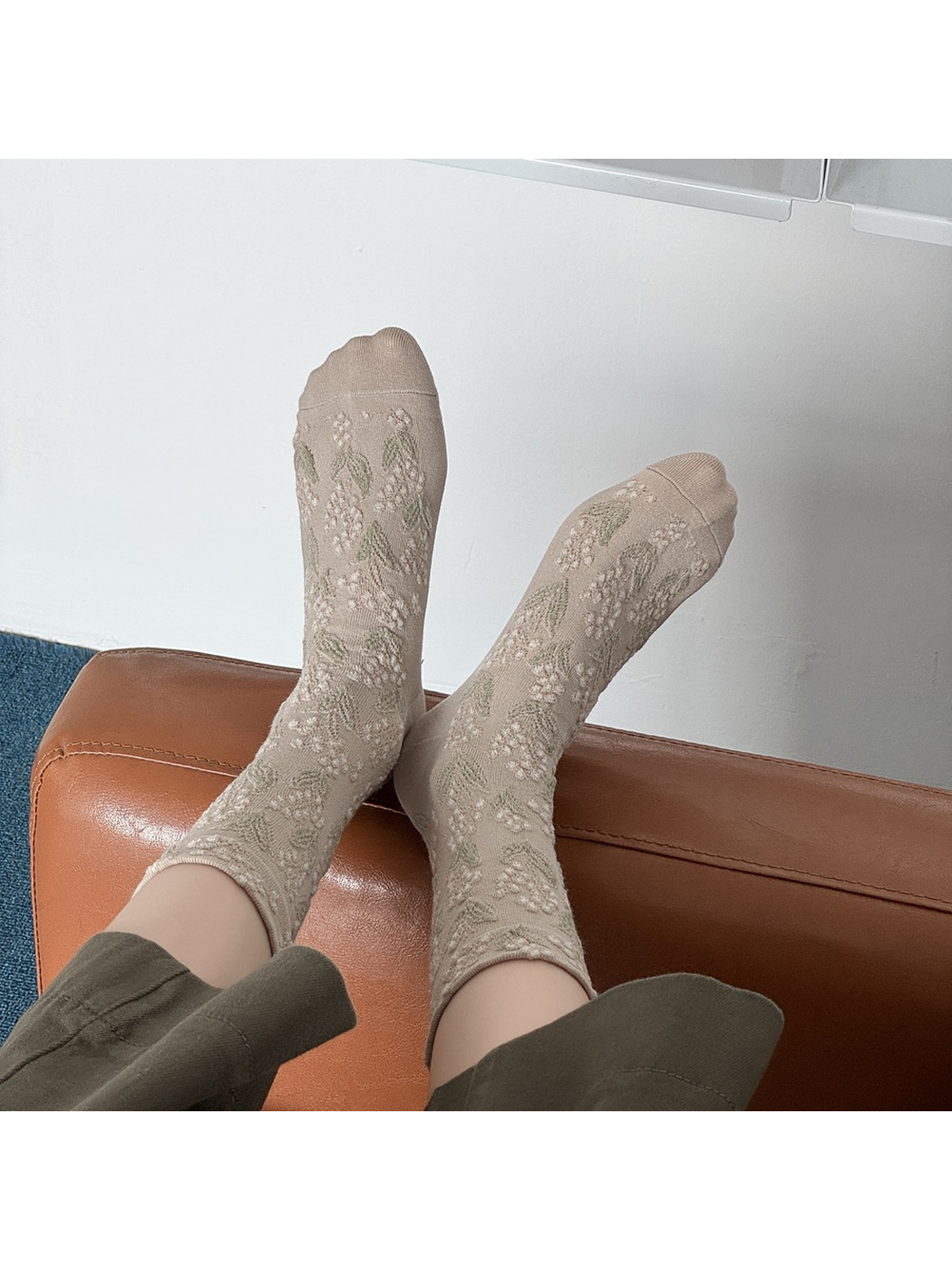 Greige floral crew socks viewed from above with both feet raised