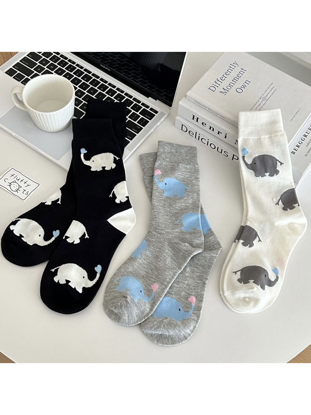 Ivory, heather gray and black crew socks with repeating elephant motifs