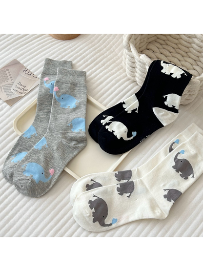 Three elephant-pattern crew sock colors arranged in a styled setting