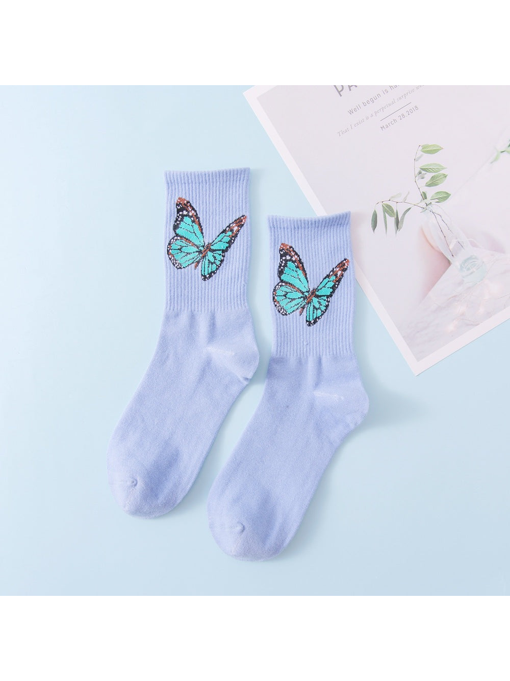 Light blue crew socks with turquoise butterfly motifs