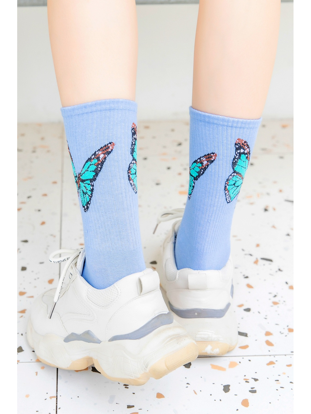 Rear view of light blue butterfly crew socks worn with white sneakers
