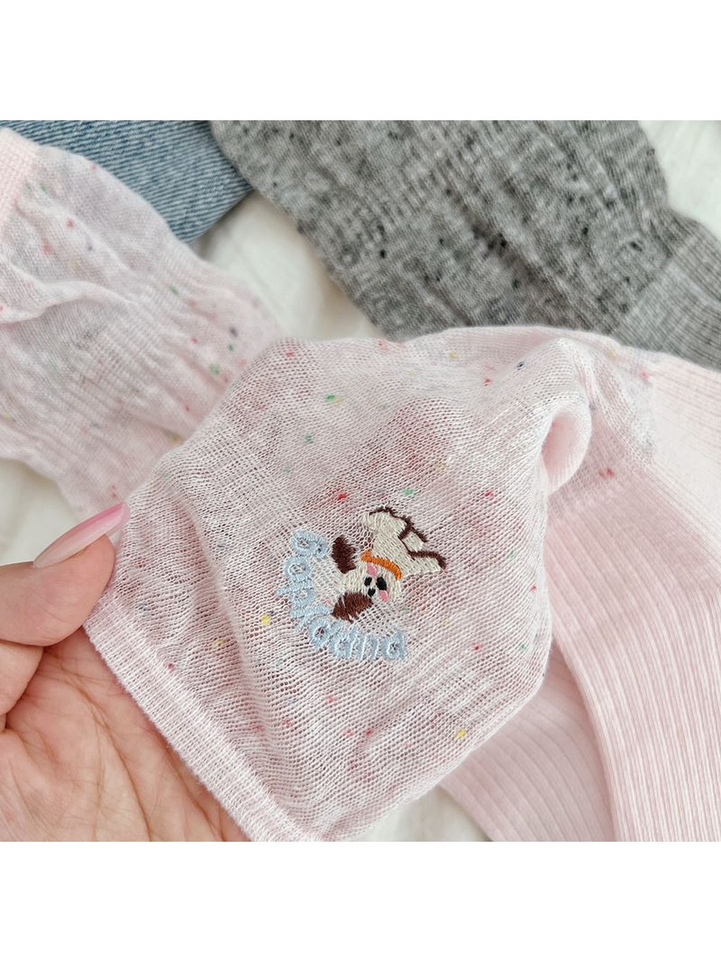 Close-up of the embroidered dog motif and multicolored flecks on a pink sock