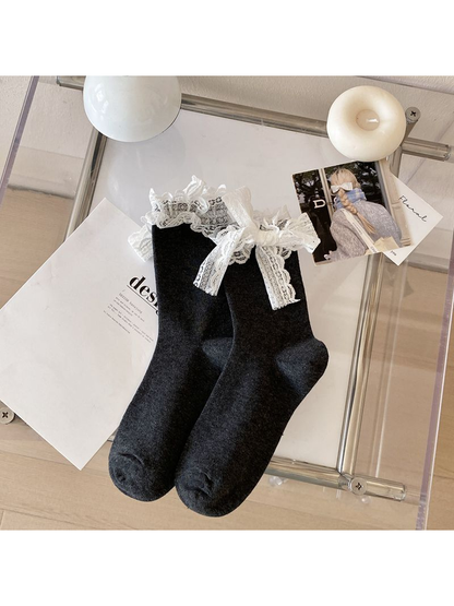 Dark gray crew socks with white lace ruffle cuffs and bows