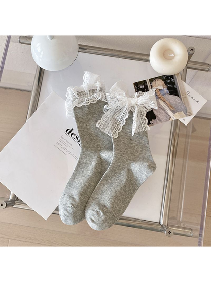 Light gray crew socks with white lace ruffle cuffs and bows