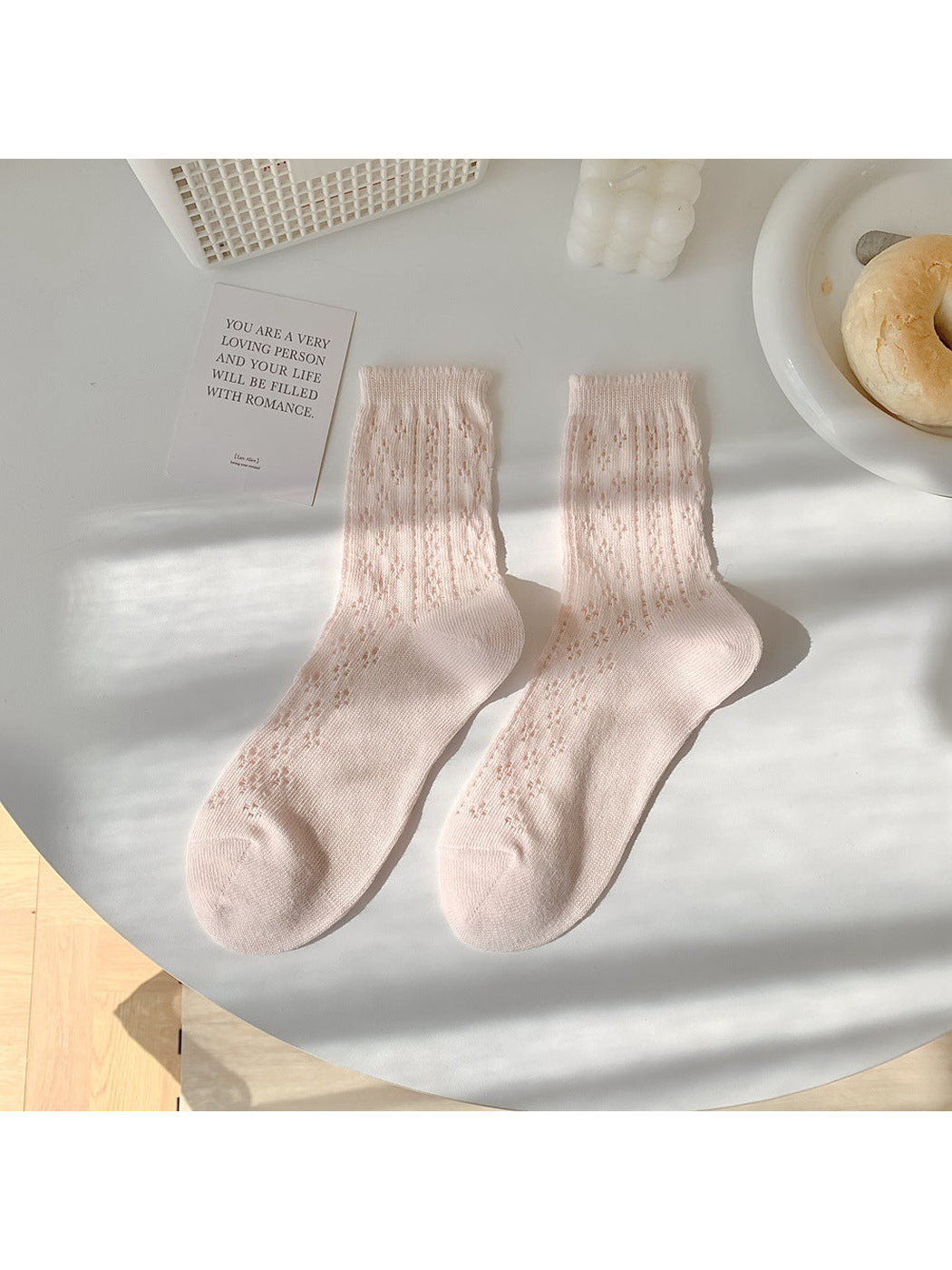 Light pink pointelle crew socks laid flat in a pair