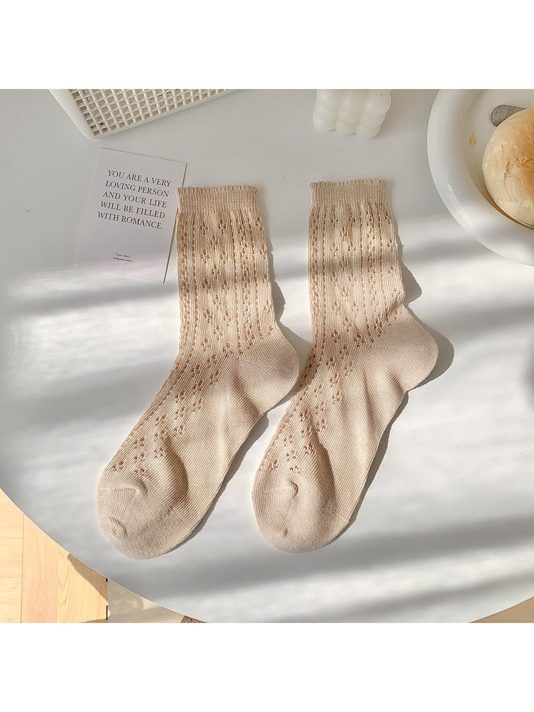 Beige pointelle crew socks laid flat in a pair