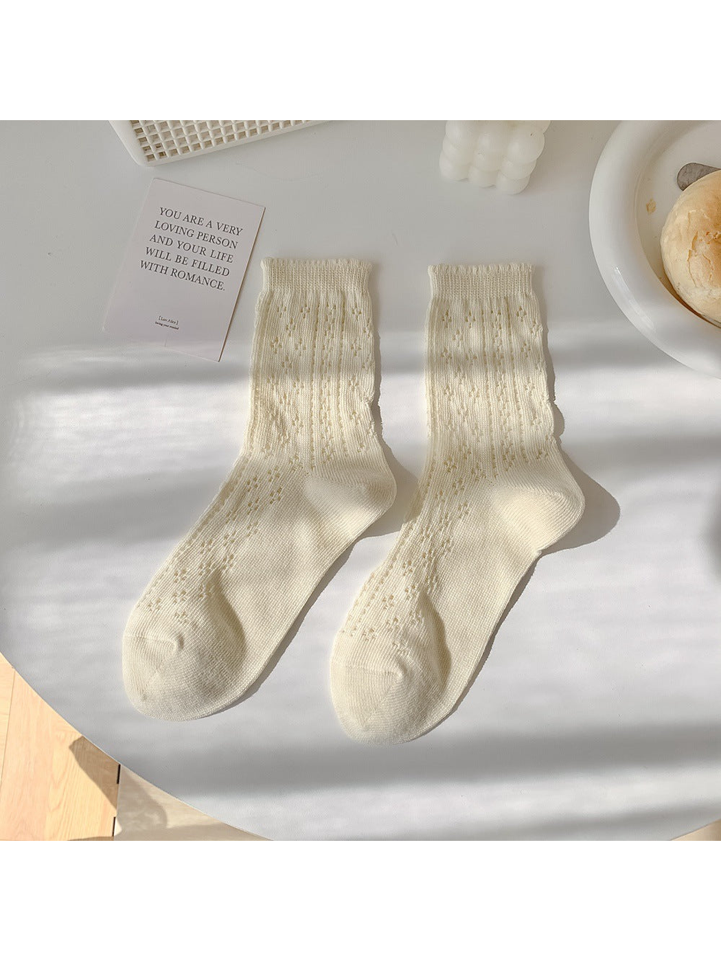 Cream pointelle crew socks laid flat in a pair