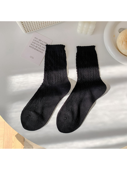 Black pointelle crew socks laid flat in a pair