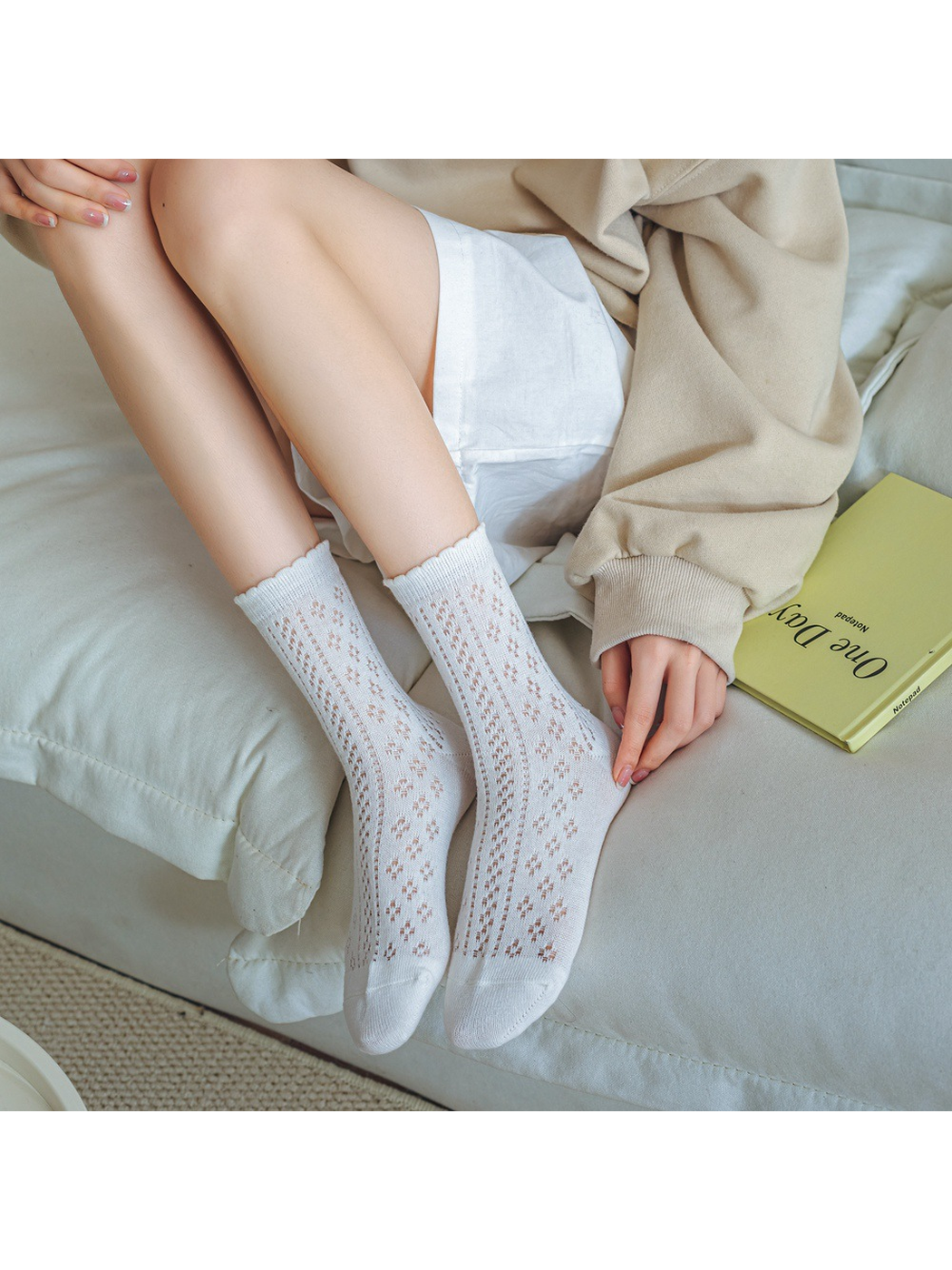White pointelle crew socks worn while seated on a sofa