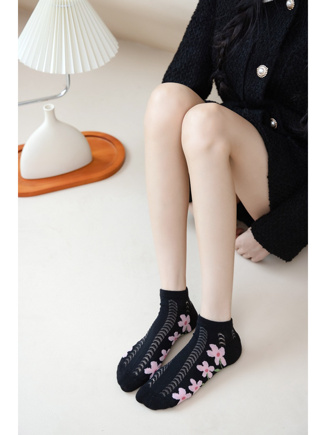 Black floral ankle socks worn in a seated indoor setting