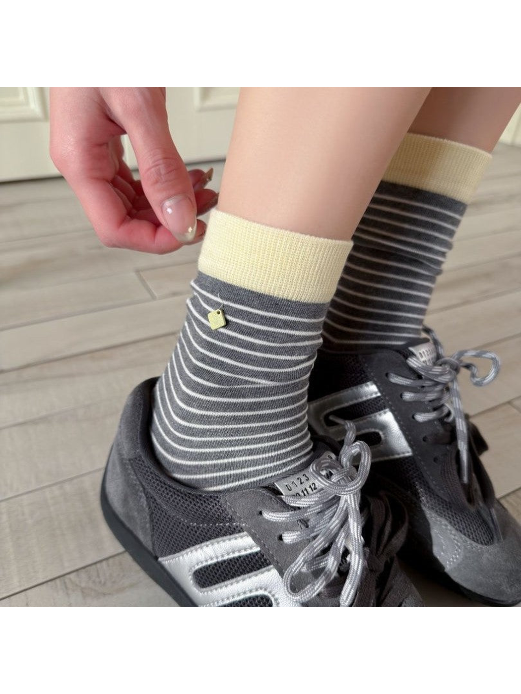 Dark gray striped crew socks with ivory cuffs styled with gray sneakers