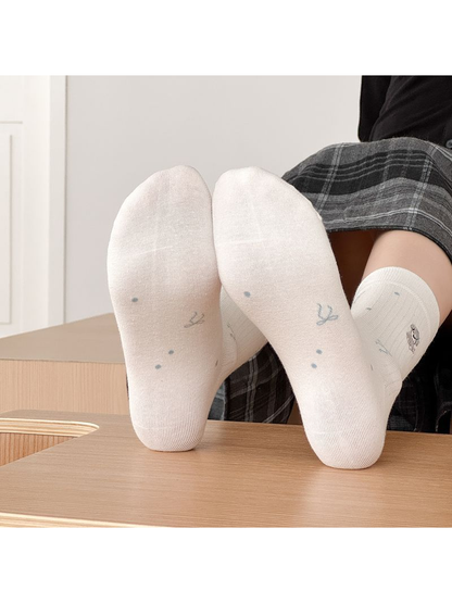 Soles of white crew socks with scattered bow and dot motifs