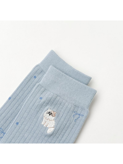 Close-up of an embroidered animal motif below the ribbed cuff of light blue socks
