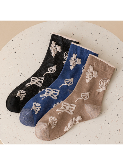 Dark gray, blue and taupe botanical crew socks displayed together