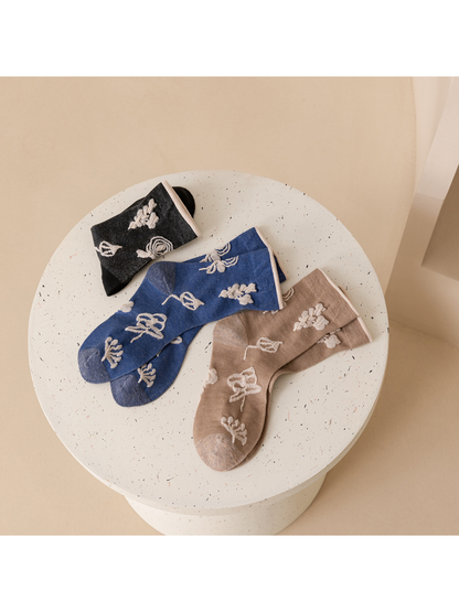 Dark gray, blue and taupe botanical socks arranged flat