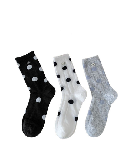 Black, white and light gray polka-dot crew socks displayed together