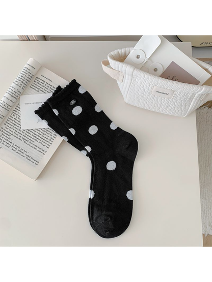 Black polka-dot crew sock displayed flat