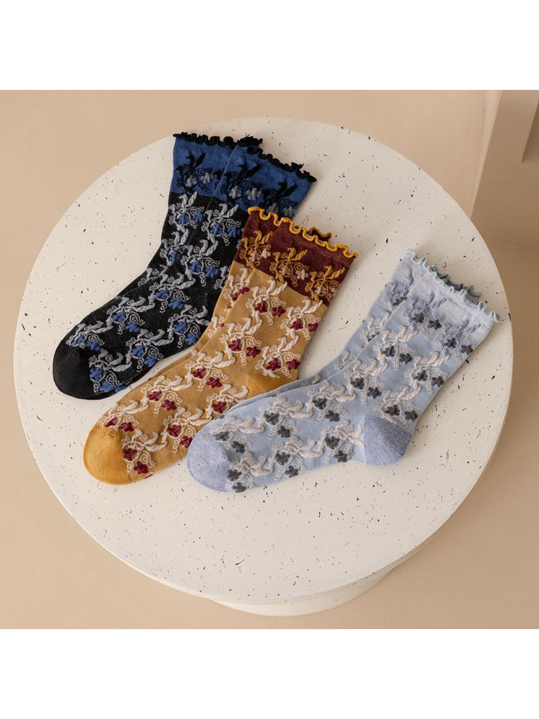Black and blue, mustard yellow, and pale blue-gray floral crew socks displayed together