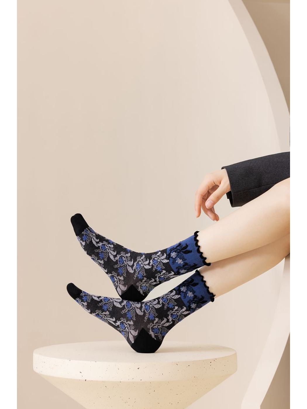 Black and cobalt-blue floral crew socks worn with the feet raised