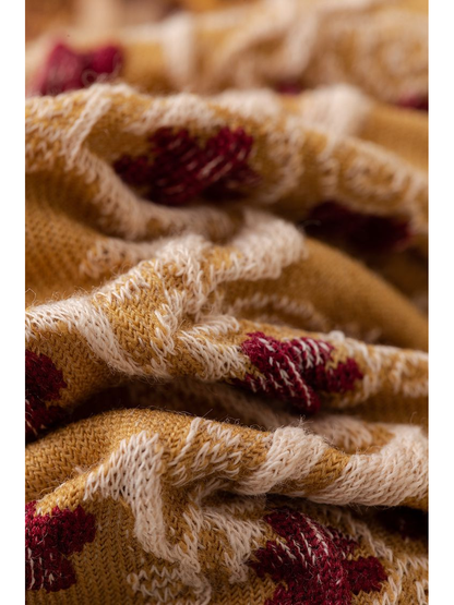 Macro close-up of the raised cream and burgundy motifs on mustard knit