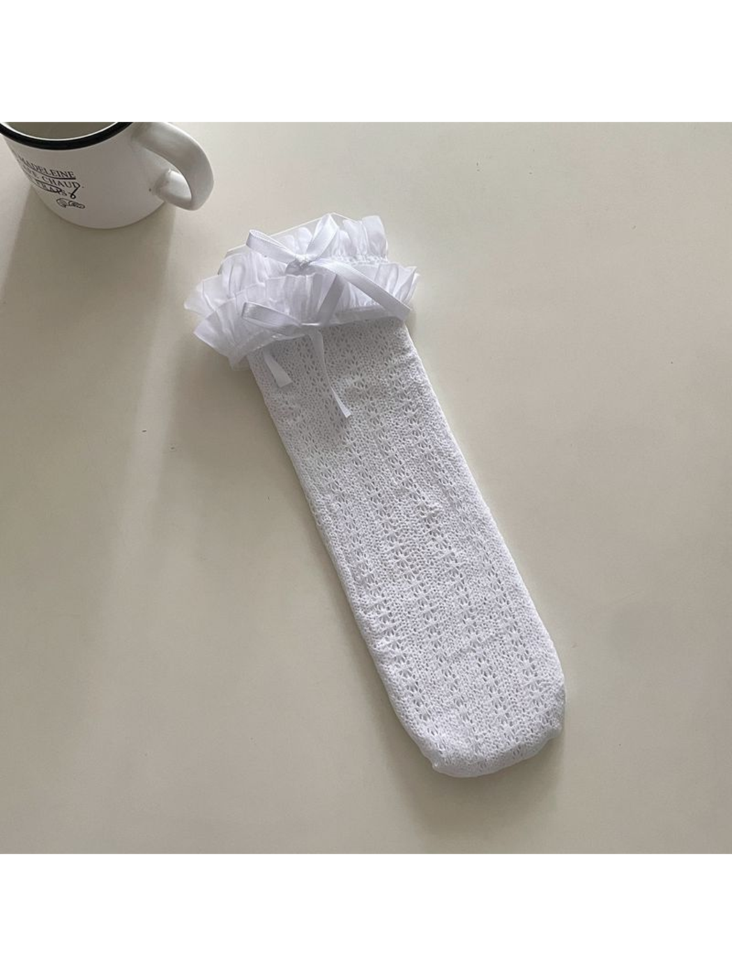 White openwork crew sock with a ruffled cuff and ribbon bow