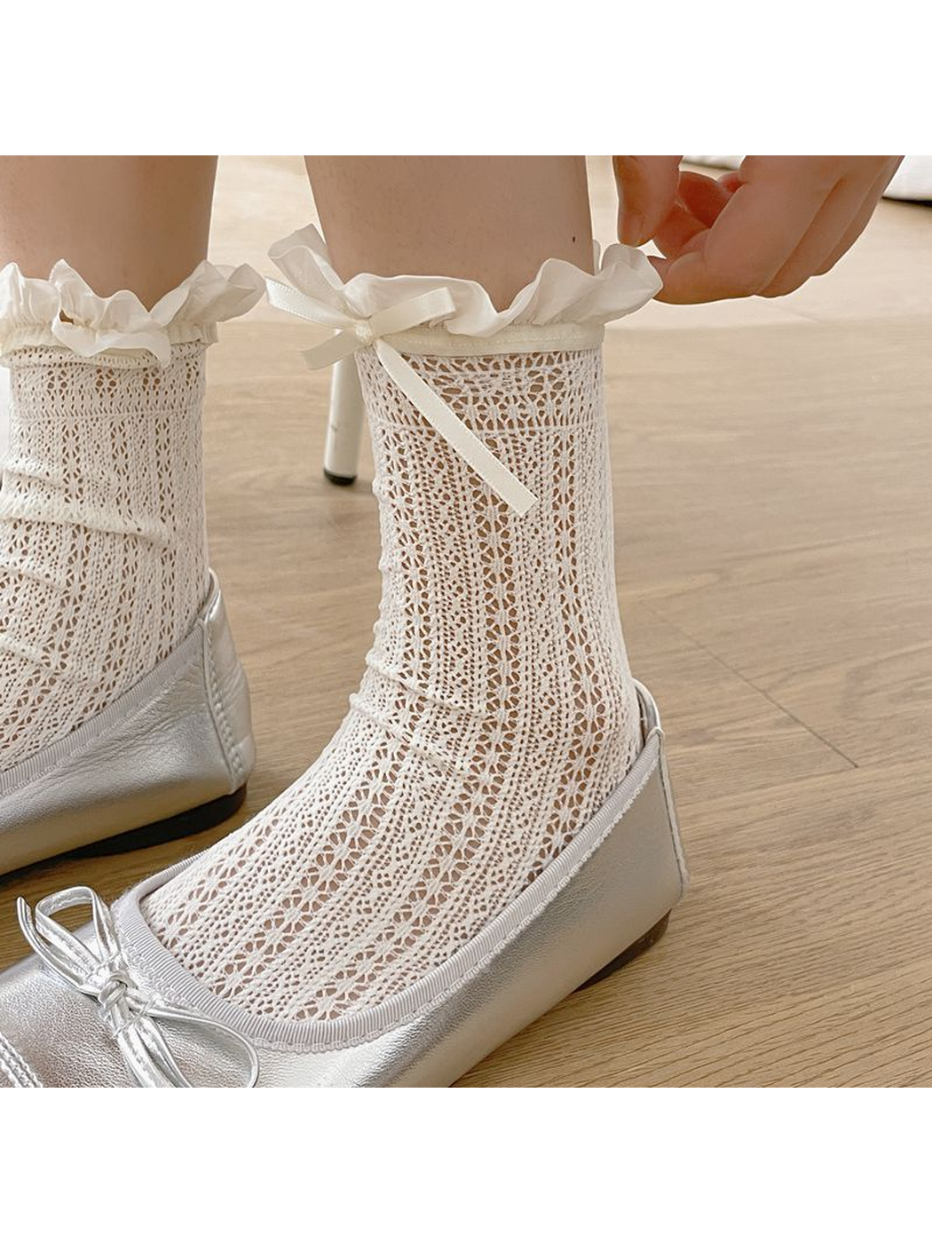 Close-up of white openwork socks with floral pointelle and ruffled bow cuffs