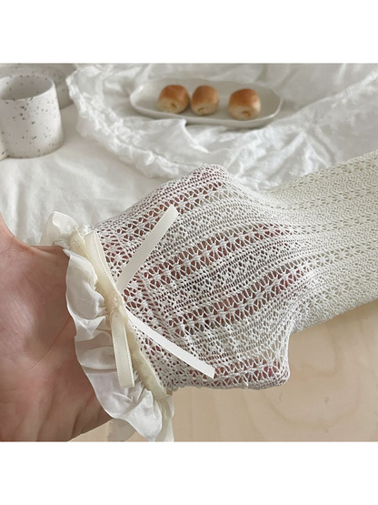 White crew sock showing floral openwork, a ruffled cuff and ribbon bow