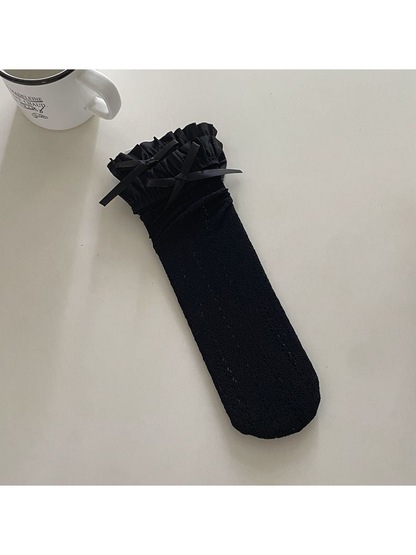 Black openwork crew sock with a ruffled cuff and ribbon bow