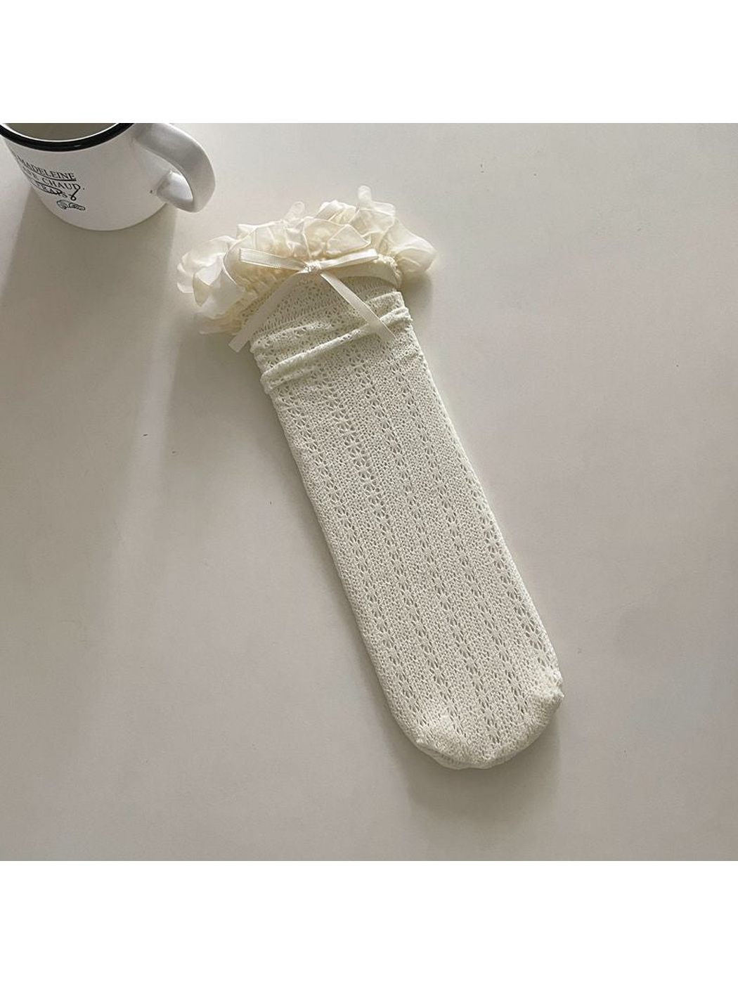 Ivory openwork crew sock with a ruffled cuff and ribbon bow