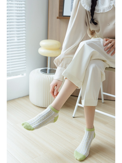 Green and white dotted ankle socks worn in a seated indoor setting