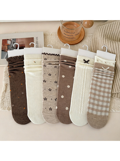 Six brown, beige and ivory crew sock styles arranged in a neutral flat lay