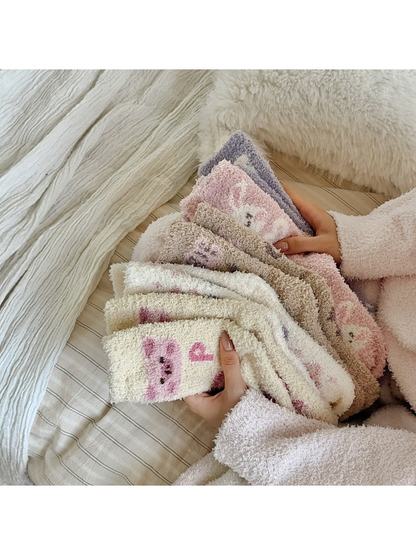 Assorted fuzzy patterned crew socks held together on a bed