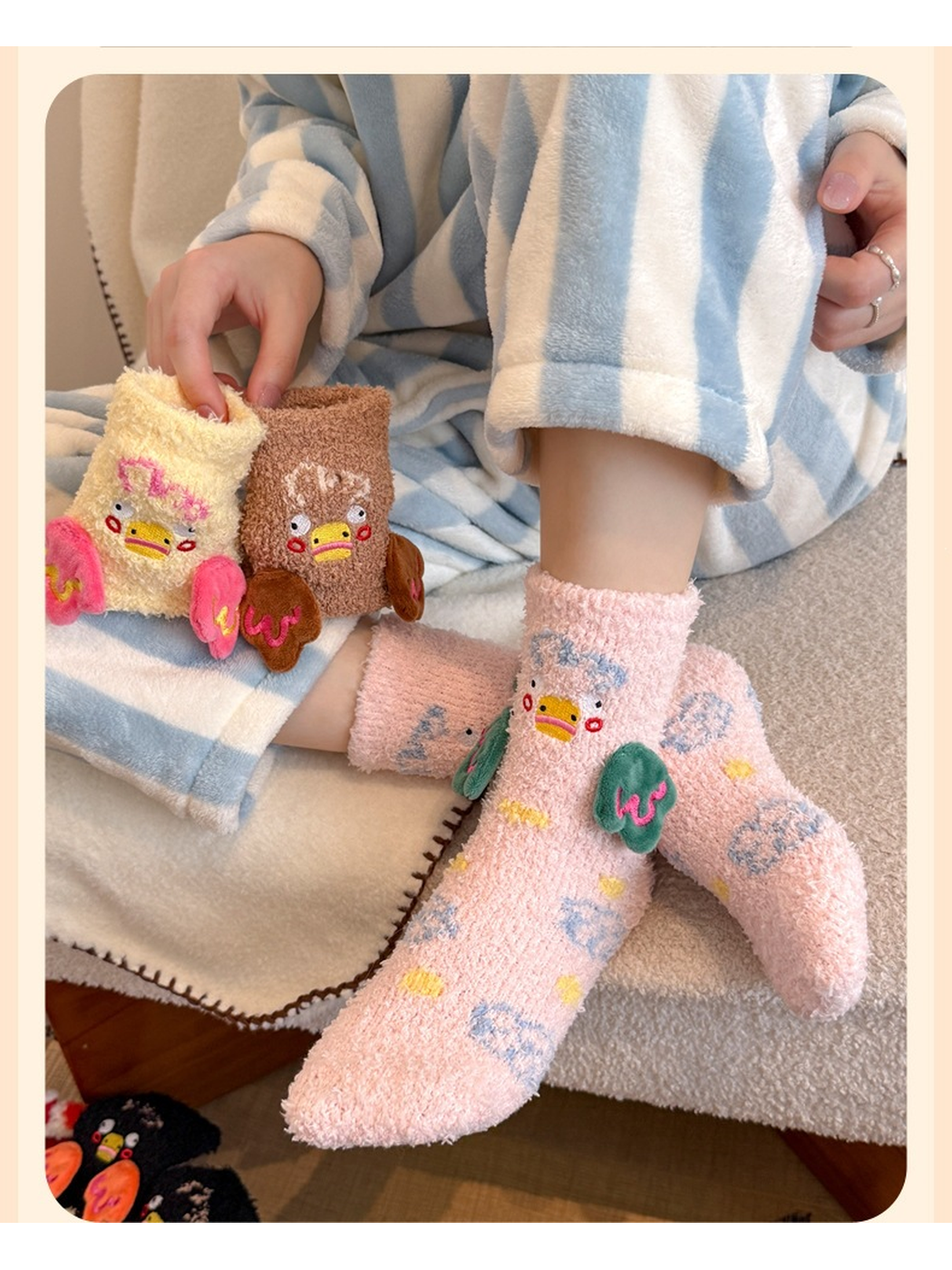 Pink duck-motif crew socks worn while cream and brown colorways are held nearby