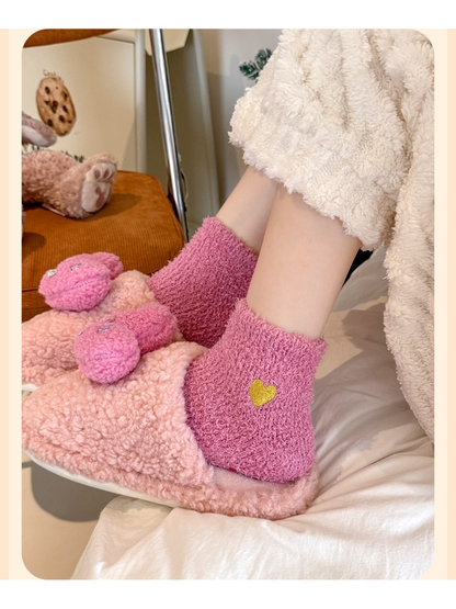 Dusty pink fuzzy ankle socks with yellow heart embroidery worn with plush slippers