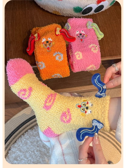 Pale yellow fuzzy sock stretched by hand with pink and orange styles nearby