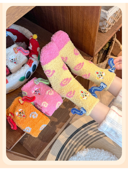 Pale yellow fuzzy crew socks viewed from above with pink and orange styles nearby