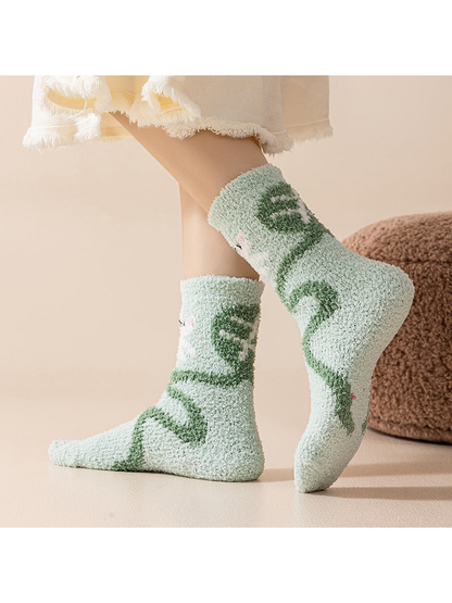 Mint crew socks with a winding green animal motif, worn view