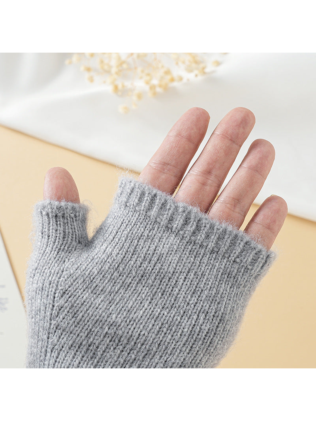 Light gray fingerless glove worn with the fingers and thumb exposed
