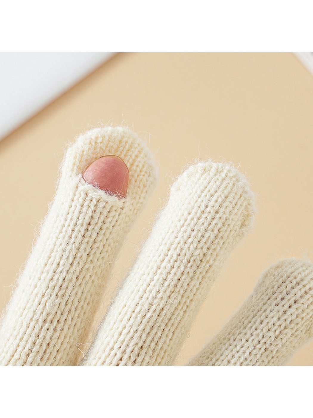 Close-up of the thumb-tip opening on ivory knit gloves