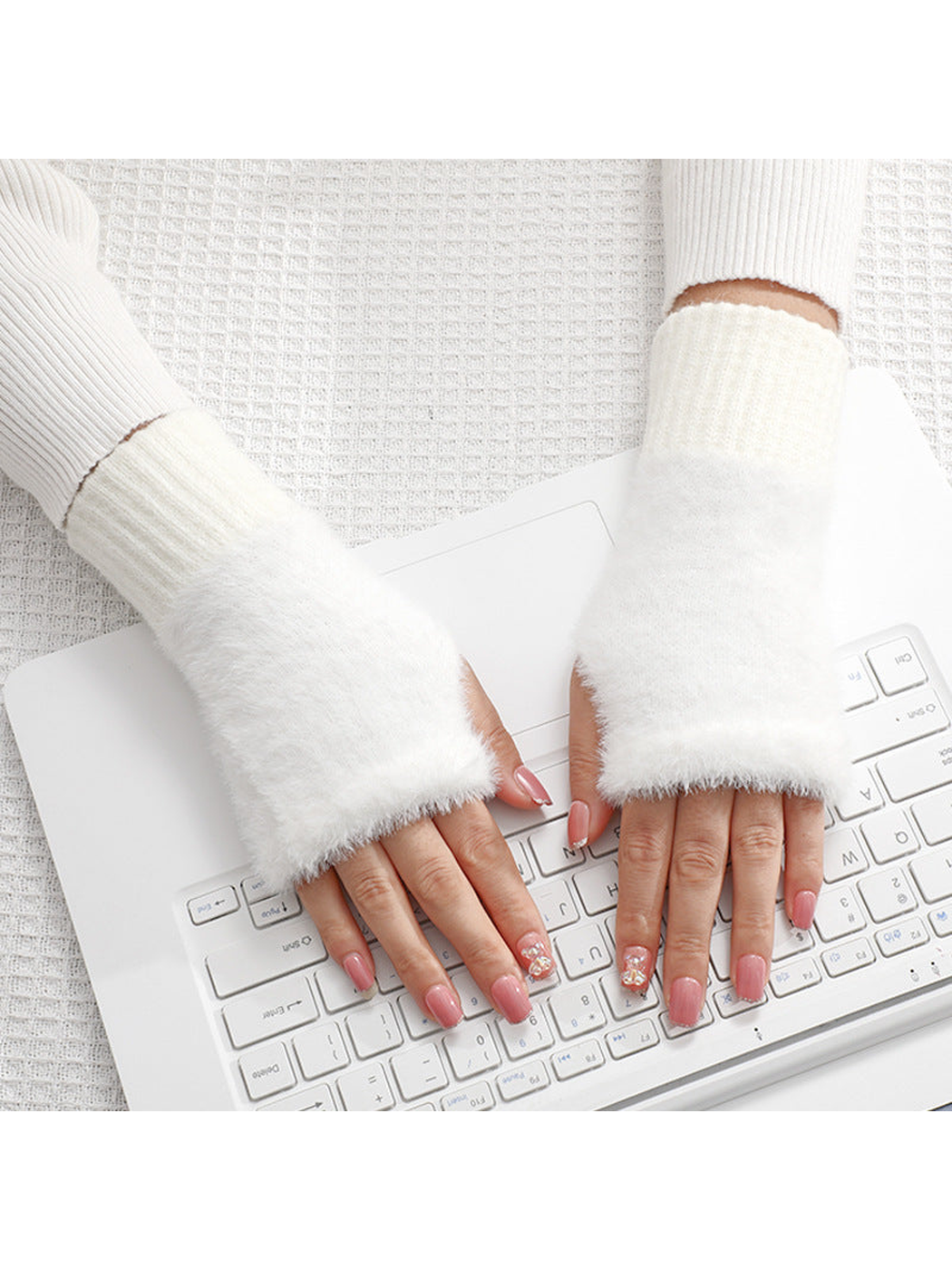 White fuzzy fingerless gloves worn over the hands