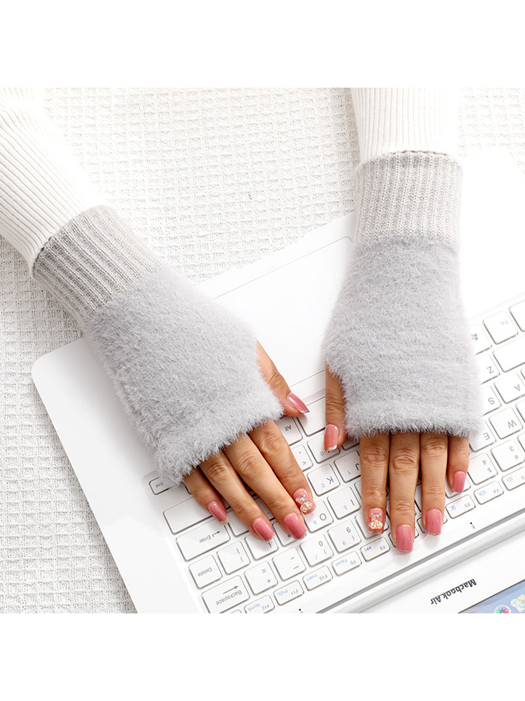 Light gray fuzzy fingerless gloves worn over the hands