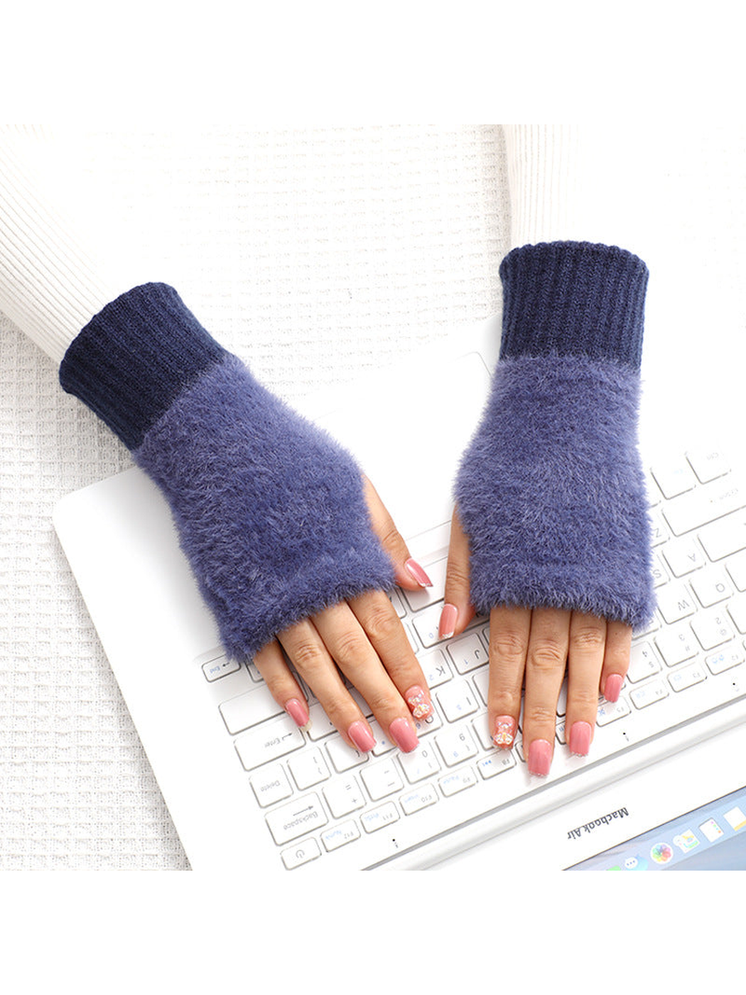 Navy fuzzy fingerless gloves worn while using a keyboard