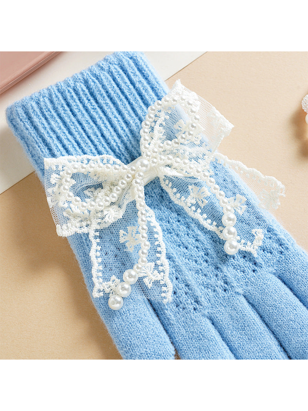 Close-up of the lace bow and bead-like trim on a light blue glove